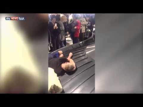 مسافر ينام على مسار الحقائب في المطار